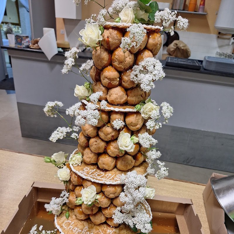 Une pièce montée haute de choux montés en tour, décorée de fleurs blanches